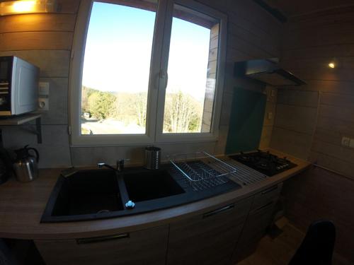 une cuisine avec un évier et une fenêtre dans l'établissement Maison avec piscine couverte 8 chambres 22 personnes au coeur de la nature, à Saint-Sauveur-en-Rue