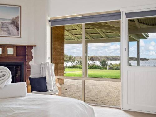 ein Schlafzimmer mit einem Bett und einer Glasschiebetür in der Unterkunft Pelicans View a Riverside Retreat in Augusta