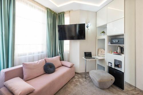 a living room with a pink couch and a tv at Aurora Hills Hotel in Plovdiv