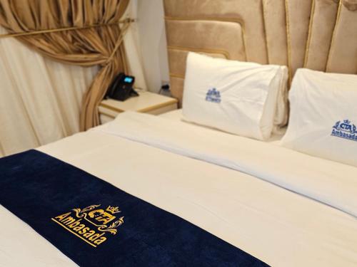 a hotel room with a bed with white sheets and pillows at Hotel Ambasada QTA in Patza-Kuqani