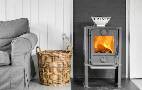 a wood stove in a living room with a couch and a basket at Beautiful Home In Nykøbing Sj With Wifi in Nyrup