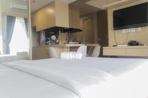 a large white bed in a room with a kitchen at Comfort Minimalist Studio at Parkland Avenue Apartment By Travelio in Tangerang