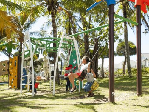 a woman sitting on a swing at a playground at Sun House -Villa Sealink Phan Thiết - Mũi Né in Phan Thiet