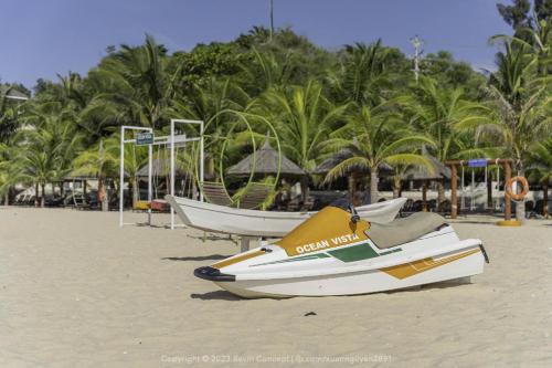 a boat on a beach with palm trees in the background at Sun House -Villa Sealink Phan Thiết - Mũi Né in Phan Thiet