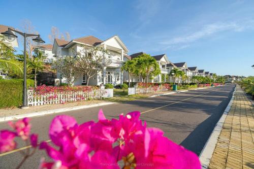 a row of houses on a street with pink flowers at Sun House -Villa Sealink Phan Thiết - Mũi Né in Phan Thiet