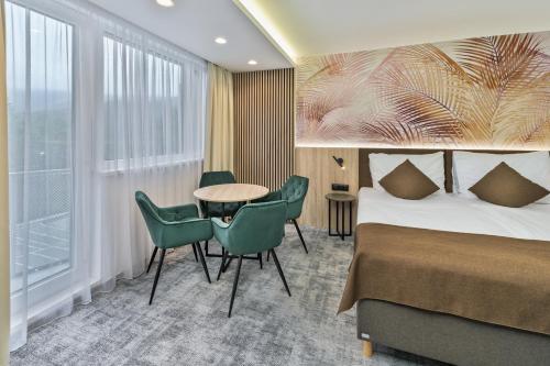 a hotel room with a bed and a table and chairs at Wellness Hotel Astra in Špindlerův Mlýn