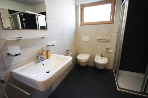 a white bathroom with a sink and a toilet at Aurturist Villabassa in Villabassa