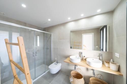 Un baño con dos lavabos, una ducha y un espejo. en Villa Borghese, en San José