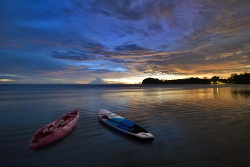 two boats sitting in the water at sunset at Twin Lotus Resort and Spa - SHA Plus - Adult Only "November - April" in Ko Lanta