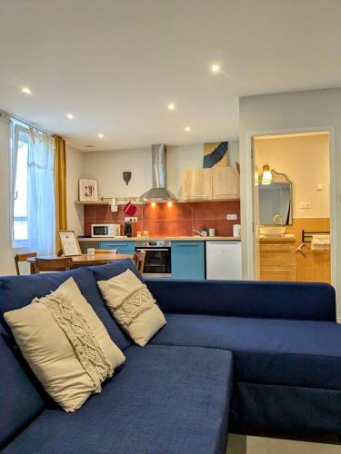 a living room with a blue couch and a kitchen at Le Riad, sauna & jacuzzi in Riorges