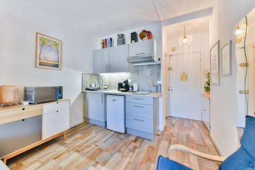 une cuisine avec des armoires blanches et un plancher en bois dans l'établissement LE FESTIF splendide studio avec loggia au Carré d'Or, une joie spéciale pour deux, à Cannes