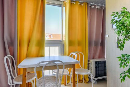 une table et des chaises dans une pièce avec des rideaux dans l'établissement LE FESTIF splendide studio avec loggia au Carré d'Or, une joie spéciale pour deux, à Cannes