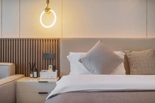 a bedroom with a bed with white sheets and pillows at Meet at Kunming Colorful Gate Shangpin Apartment in Kunming