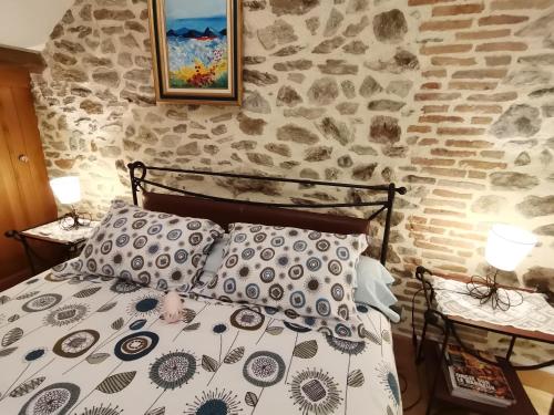 a bedroom with a stone wall and a bed with pillows at La petite porcherie in Ladignac-le-Long
