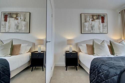 a bedroom with two beds and two lamps and a mirror at Clover lodge Portsmouth luxury home with off road free parking in Portsmouth