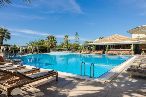 a large swimming pool with chaise lounges next to a resort at Avithos Resort Hotel in Svoronata