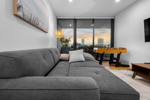 a living room with a gray couch and a table at The Riviera - Brand New Luxury River Front 2 Bedroom Unit with Parking & Pool in Gold Coast