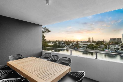 a balcony with a wooden table and chairs at The Riviera - Brand New Luxury River Front 2 Bedroom Unit with Parking & Pool in Gold Coast