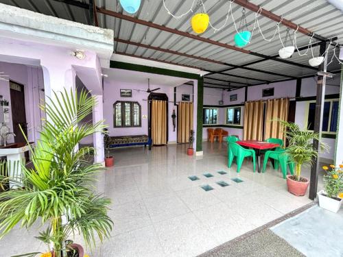 a living room with a red table and green chairs at Krishna Kunj Homestay Rishikesh in Rishīkesh