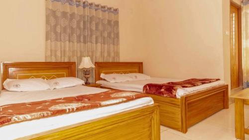 two beds sitting in a room with a window at Hotel Sikder Residential Mirpur in Bisil