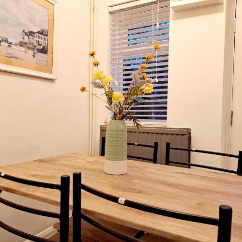 a vase of flowers sitting on a wooden table at 2 Bedroom House in Leeds - Sleeps 5 WiFi Parking in Leeds