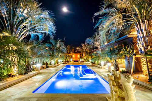 a pool with palm trees and a hotel at night at Sunrise Villa Oarai in Natsumi