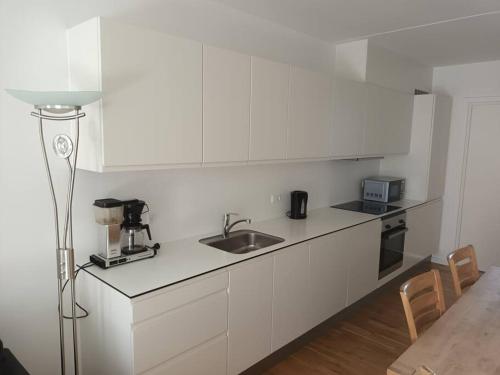 Una cocina con gabinetes blancos y un fregadero y una lámpara. en Fully equipped apartment, 15 min to Center, en Copenhague