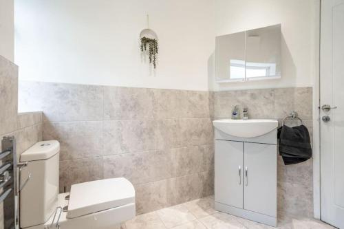 a bathroom with a white toilet and a sink at Pool Table - Spacious and Tranquil Hideaway - Near Airport - Sleeps 10 in Broadheath