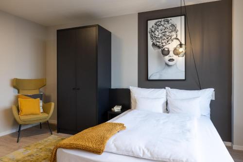 a bedroom with a white bed and a chair at Numa Cologne Ehrenfeld in Cologne