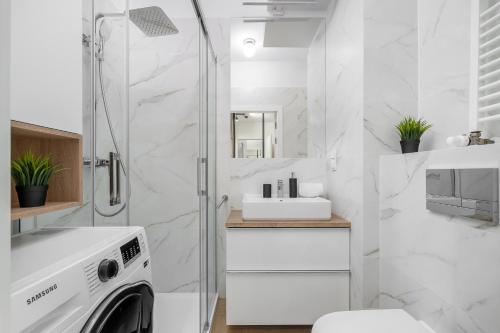 a white bathroom with a shower and a washing machine at MARGI Flair Apartament POOL SAUNA JACUZZI in Szczecin