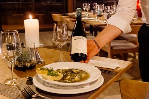 a person holding a bottle of wine and a plate of food at Beach Hotel Swakopmund in Swakopmund