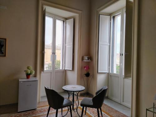 a room with chairs and a table and windows at Palazzo Castellano in Lecce