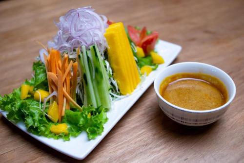 a plate of vegetables and a bowl of dipping sauce at Nsaho resort in Fort Portal