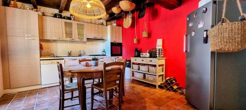 une cuisine avec des murs rouges et une table et des chaises dans l'établissement La-Nadalie, à Marval
