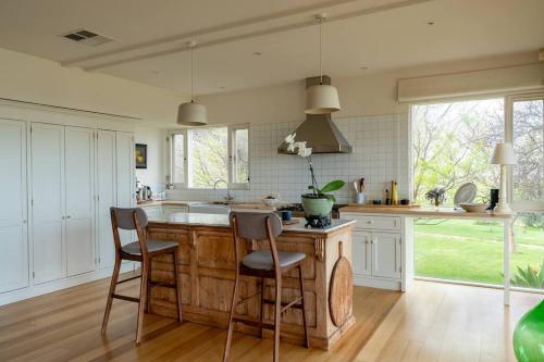 a kitchen with a wooden island with two chairs at Bayview Farm Bashams in Port Elliot