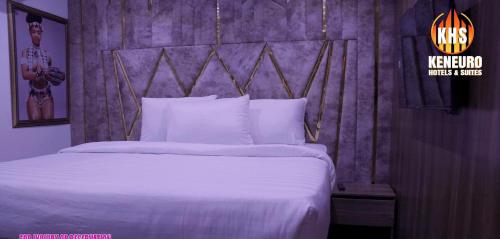 a bedroom with a white bed with a wooden headboard at Keneuro hotel & suites in Lagos