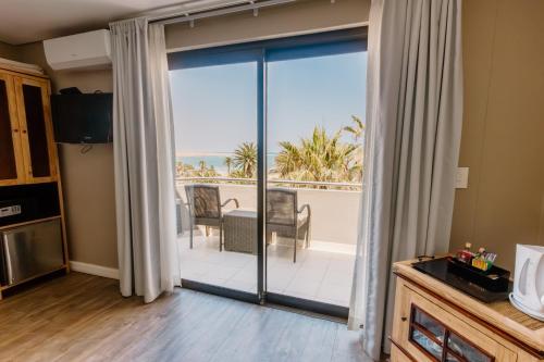 a living room with a sliding glass door with a view of the ocean at Beach Hotel Swakopmund in Swakopmund