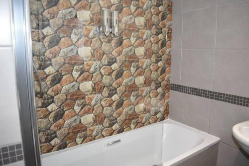 a bathroom with a shower with a stone wall at Chic Oasis in Vibrant Jozi BDC in Johannesburg