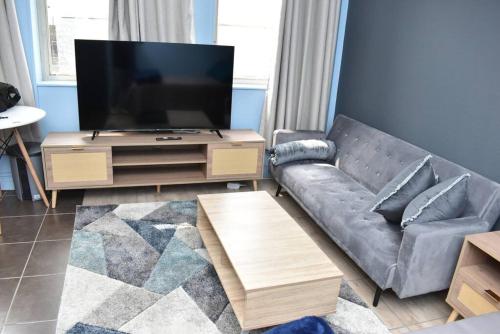 a living room with a couch and a flat screen tv at Chic Oasis in Vibrant Jozi BDC in Johannesburg