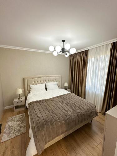 a bedroom with a large bed and a chandelier at Porcelain Apartment in Rădăuţi
