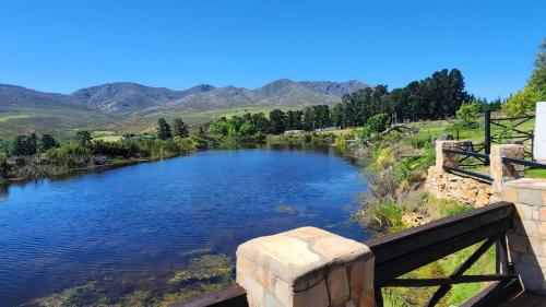 a bridge over a river with mountains in the background at Mountain Pastures Game Lodge in Uniondale
