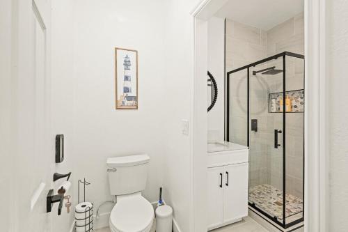 a white bathroom with a toilet and a shower at Cozy Retreat Near Downtown - Perfect for Families in Long Beach