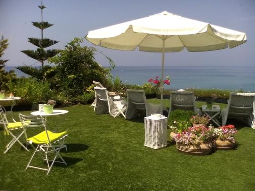 a group of chairs and an umbrella on the grass at Palmina Mare Villa and Studios in Paralia Vrachou
