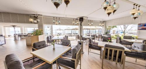 a restaurant with tables and chairs and windows at Effect Algara Beach Resort - Ultra All Inclusive and Free Parking in Kranevo