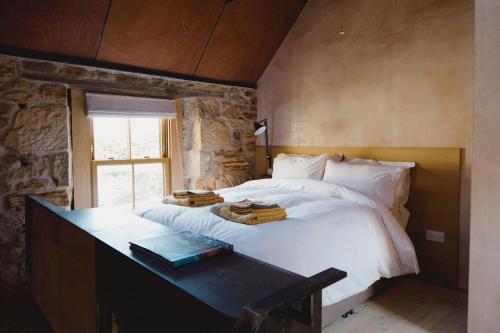 a bedroom with a large white bed with a table at The Old Stable - Your Seaside Hideaway in Pittenweem