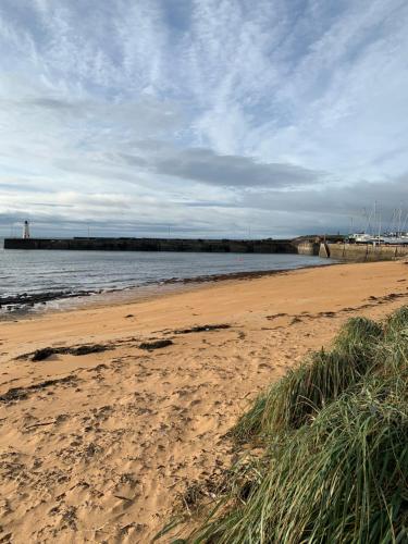 a sandy beach with a pier in the water at New Holliday Villa, Anstruther in Cellardyke