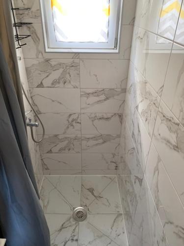 a bathroom with a shower with marble tiles at Mariyka Apartaments 2 in Sutomore