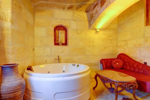 a bathroom with a white tub and a red couch at Mizan Cave Cappadocia in Nevsehir