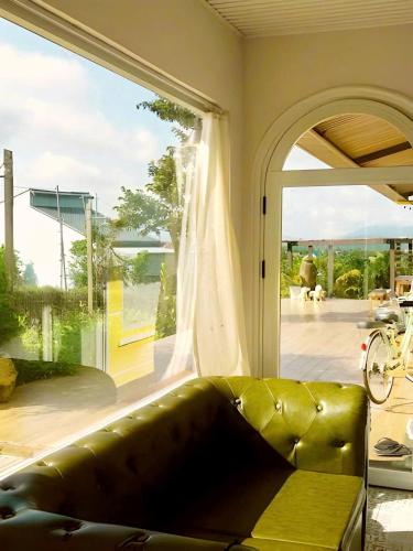 a leather couch in front of a large window at Adachi Farmstay Bảo Lộc in Bao Loc