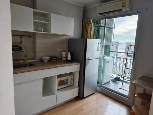 a kitchen with a white refrigerator and a balcony at LumpiniC17 in North Pattaya